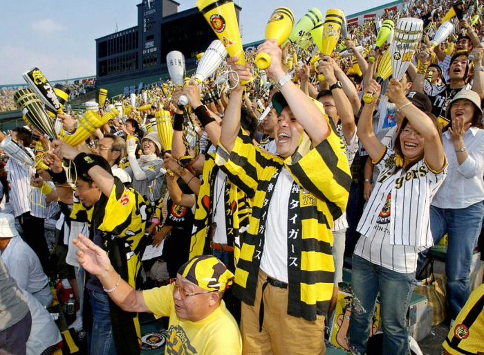 Поклонники Hanshin Tigers празднуют, как команда выиграла свой первый чемпионский титул за 18 лет на стадионе Koshien в Нисиномии, недалеко от Осаки, 15 сентября 2003 г.