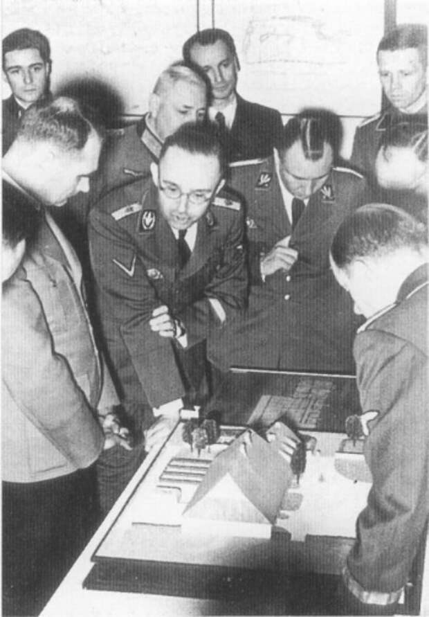 Выставка 'Строительство и планирование на Вос­токе' , Берлин 20. 3.1941 г. Рейхсфюрер СС Генрих Гиммлер, здесь в качестве рейх­скомиссара по укреплению немецкой народности, объ­ясняет 'заместителю фюрера' Рудольфу Гессу (слева рядом с Гиммлером) проект поселений в завоеванных польских областях