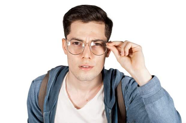 A person squints and puts their hands on their eyeglasses.
