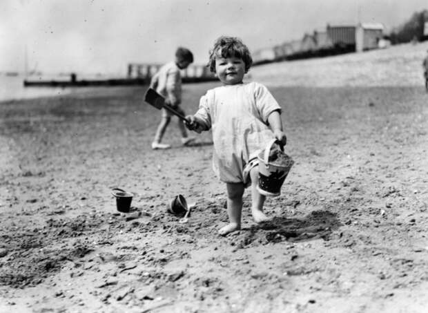 Ведёрко и лопатка - неизменные атрибуты детских игр на пляже вот уже почти 100 лет. Ребёнок на пляже в Саутенд. Англия, 1922 год.