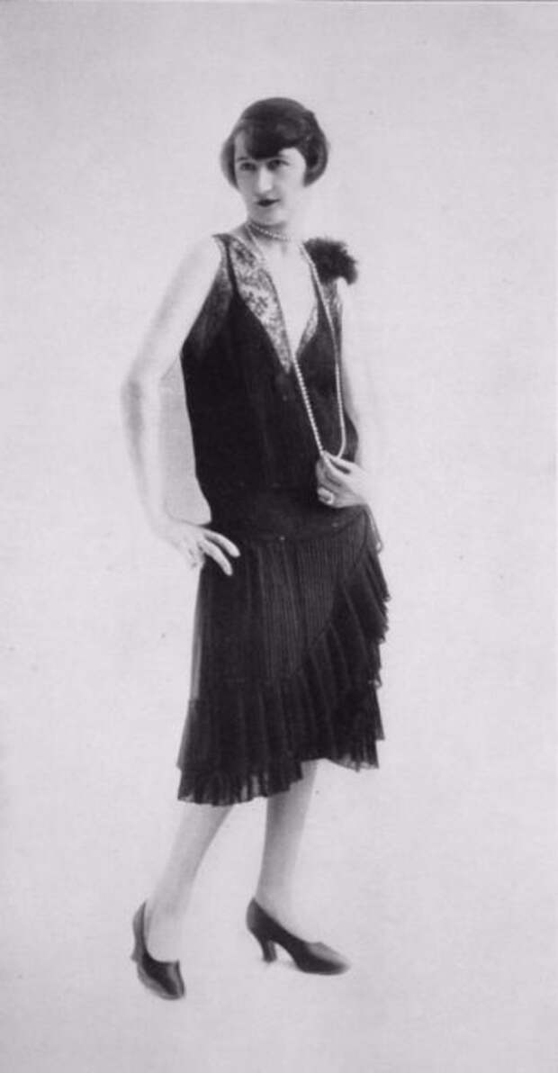 Плиссированное платье с мелкими рюшами и длинной ниткой жемчуга.