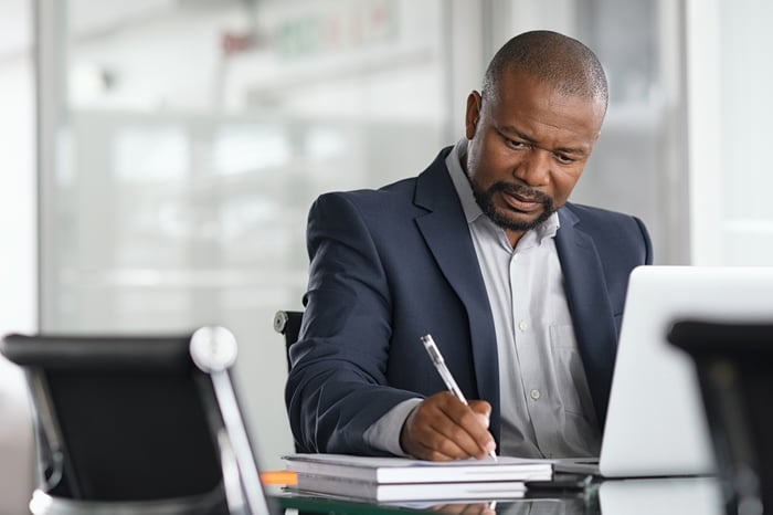 A person at a laptop taking notes.