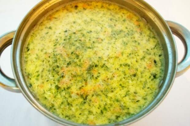 Спустя 5 минут запустите плавленные сырки, мелко нарезанную зелень и оставьте суп на огне помешивая, пока сыр полностью не растворится (3-5 минут).