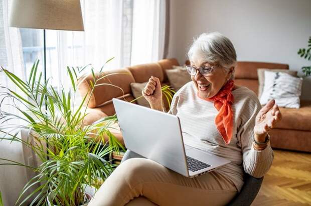 Elderly person excited about something they see on a laptop screen.