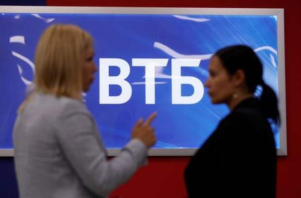 Employees pose for a picture near a board showing the logo of VTB during a tour at a branch of VTB bank in Moscow, Russia May 30, 2019. REUTERS/Evgenia Novozhenina