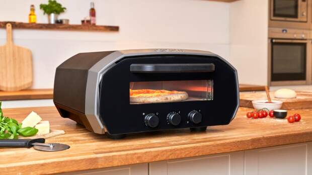 The Ooni Volt 12 electric pizza oven in a kitchen setting, cooking a pizza