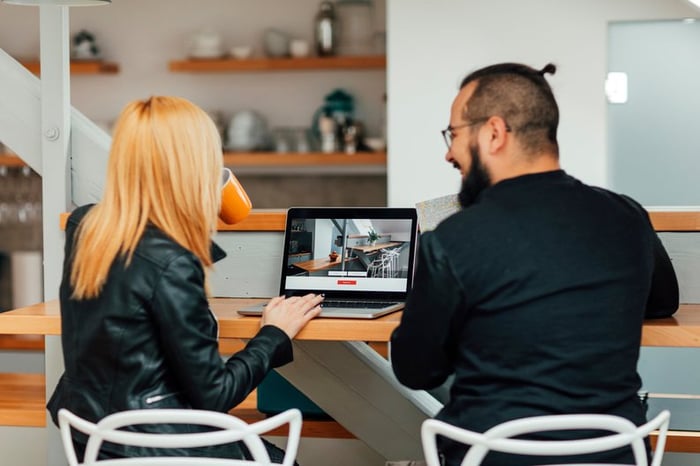 Man and woman look at homes on a laptop.