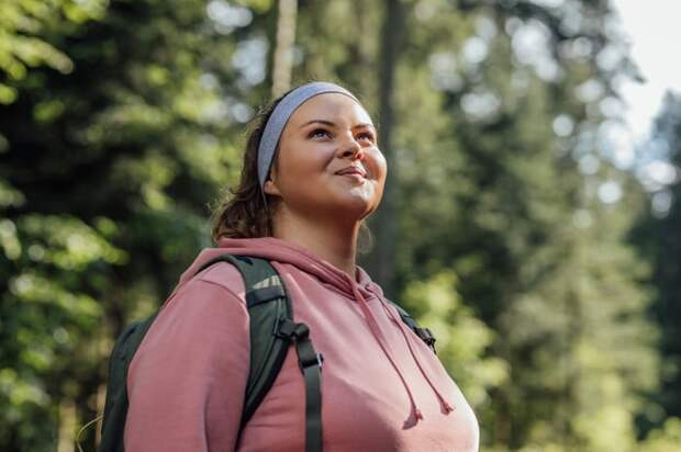 Someone is hiking outside and looking up with a slight smile.