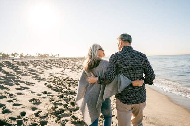 Two people walking on a beach and hugging.