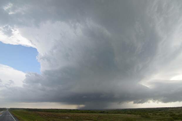 a photo of a supercell cloud in the distance towering over the horizon