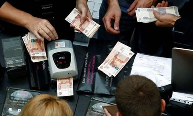 A shop assistant (L) counts Russian rouble banknotes as customers gather at a store selling Apple products during the launch of the new iPhone 7 sales at the State Department Store, GUM, in central Moscow, Russia September 23, 2016. REUTERS/Sergei Karpukhin