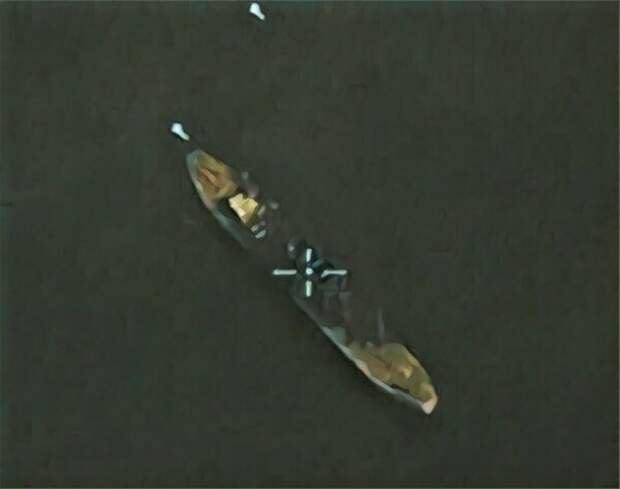 Два белых предмета возле силуэта судна,подлетающие ракеты "Каяк". Судно частично затоплено предыдущими попаданиями.