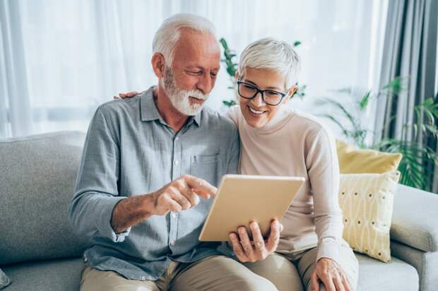 Two people on a couch looking at a tablet.