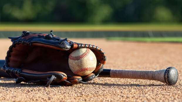 baseball glove and bat on infield dirt