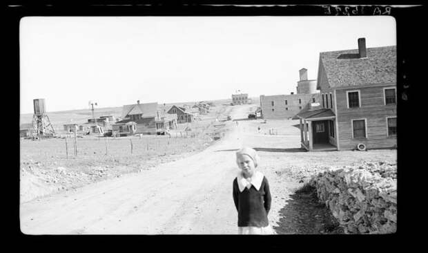 Девочка у дороги, ведущей к городку Миллс графства Хардинг. Фотограф отметила, что элеватор и городской банк были на тот момент закрыты из-за пыльных бурь и Великой Депрессии. 30-е годы, америка, великая депрессия, исторические кадры, история, редкие фото, сша, фото