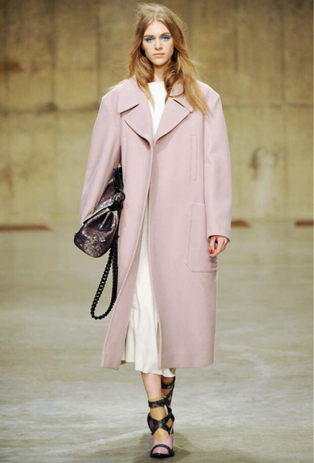 Модель в розовом пальто ниже колена, светлое платье и черная сумка