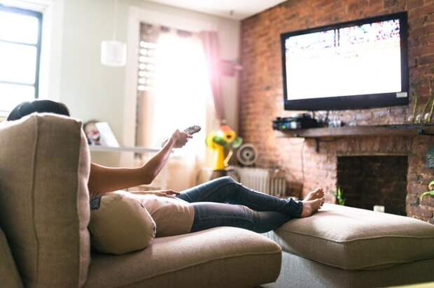 Woman lounging on her sofa watching tv.
