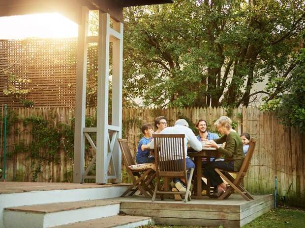 A family eating a meal at a patio table on their back deck.