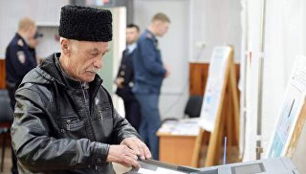 Мужчина опускает бюллетень в урну во время голосования на выборах президента Российской Федерации на избирательном участке в Симферополе.18 марта 2018