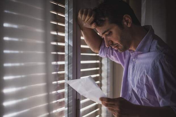 Man looks saddened by paper that he's reading.