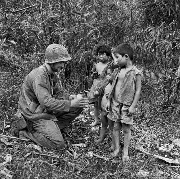 Американский солдат делится водой и едой с тремя детьми. Сайпан, 1944 года.