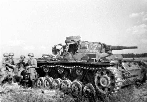 Красноармейцы на фоне танка Pz.Kpfw. III Ausf. E из 3-й танковой дивизии вермахта, подбитого под Могилевом. Прорвавшиеся к советским окопам немецкие танки были расстреляны огнем в борт и корму. С биноклем на груди командир 3-го батальона 388-го стрелкового полка капитан Гаврюшин Д.С. В руке у одного из бойца немецкий 7,92-мм авиационный пулемет MG.15. 20.07.1941. Автор: Павел Трошкин 