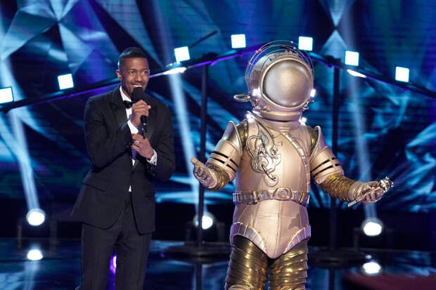 THE MASKED SINGER: L-R: Host Nick Cannon and The Astronaut in the all-new “Last But Not Least: Group C Kickoff!” episode of THE MASKED SINGER airing Wednesday, March 11 (8:00-9:01 PM ET/PT) on FOX. CR: Michael Becker / FOX. © FOX Media LLC.