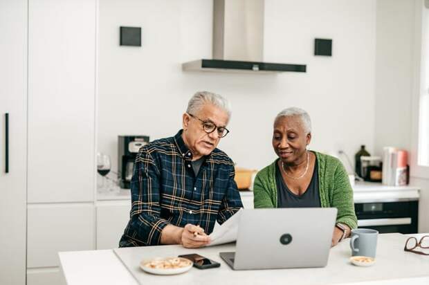 Two people looking at paperwork and a laptop.