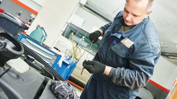 mechanic checking oil level in automobile