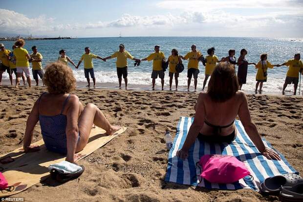 Обычные отдыхающие на пляже с изумлением смотрели на происходящее барселона, испания, каталония, местные жители, пляж, протест, протестующие, туризм