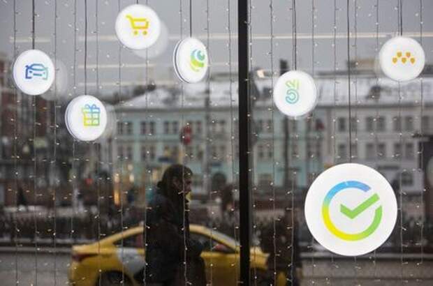 A man walks past an office of the Russian largest lender Sberbank in Moscow, Russia December 24, 2020. The logos of Sberbank ecosystem companies, which launched campaigns and new market, delivery, taxi and online cinema services, are displayed on an office window. Picture taken December 24, 2020. REUTERS/Maxim Shemetov