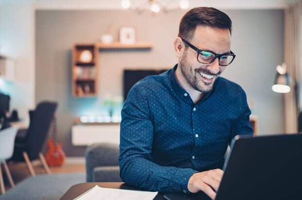 A smiling person at a laptop.