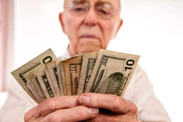 A seated person counting a fanned assortment of cash bills.