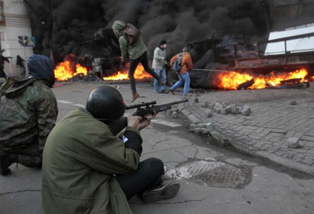 An anti-government protester shoots during clashes with riot police outside Ukraine's parliament in Kiev, Ukraine, Tuesday, Feb. 18, 2014. Thousands of angry anti-government protesters clashed with police in a new eruption of violence following new maneuvering by Russia and the European Union to gain influence over this former Soviet republic.(AP Photo/Sergei Chuzavkov)