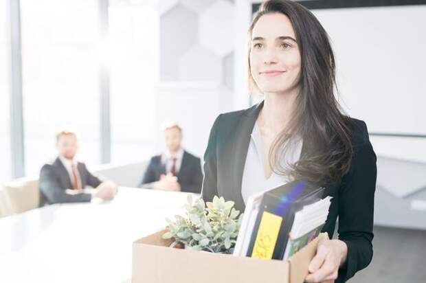 Happy businesswoman leaving job with box of belongings.