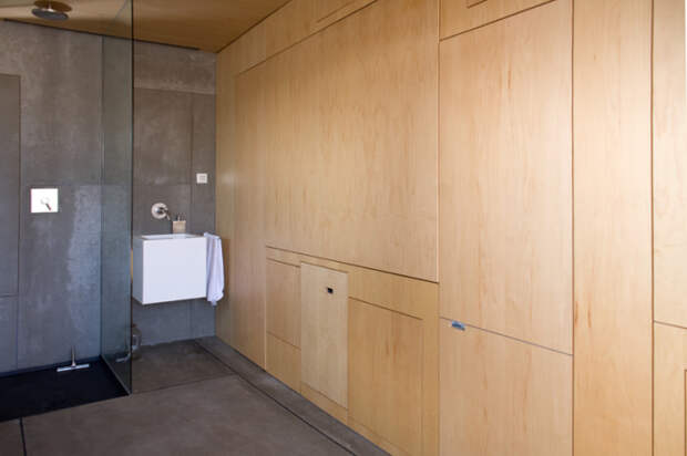 Одна из стен сделана из дерева и представляет собой уникальный многофункциональный шкаф.