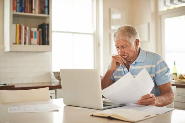 A person holding documents at a laptop.