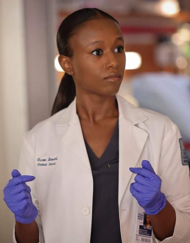 Chicago Med's Naomi wearing latex gloves and staring straight ahead