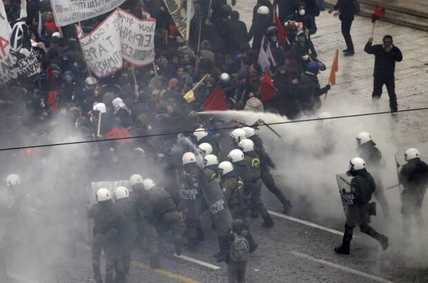 Police officers clash with protesters during riots in front of the parliament building in Athens