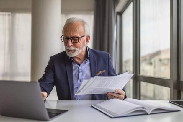 Person in office looking at papers and laptop.