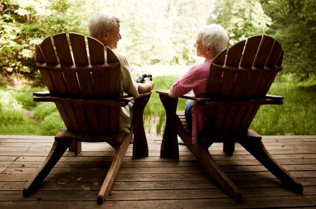 Couple sitting in chairs on porch looking out at nature.