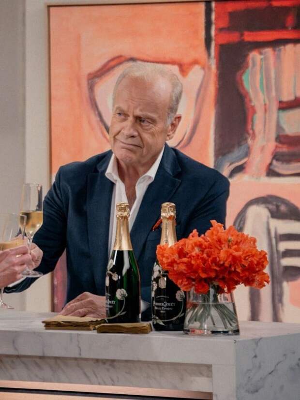 Frasier stands behind a bar with champagne