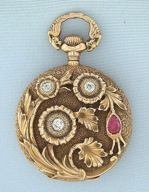 Beautiful Gruen 14K gold, diamond, and ruby beautifully decorated ladies antique pendant watch circa 1900. The case with overall engraving, the back with a high relief spray of flowers set with diamonds and a ruby. Unusual bow with mythical beasts. White enamel dial (minor hairlines) with red and gold numbers, gold and silver minute markers, and blued steel hands. Nickel 16 jewel adjusted movement.: 