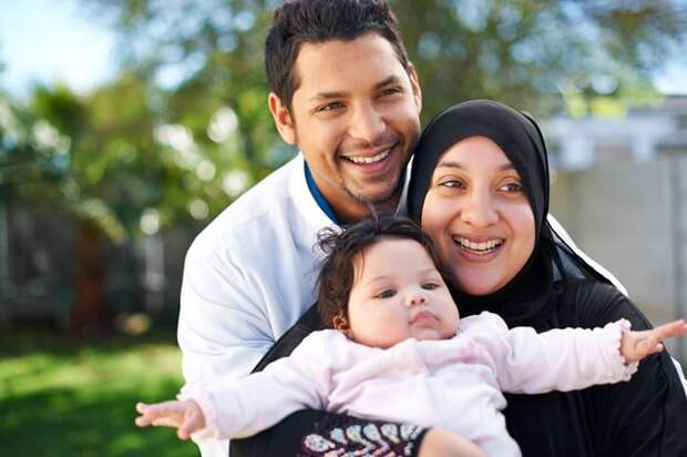 Two people hugging and holding a baby.
