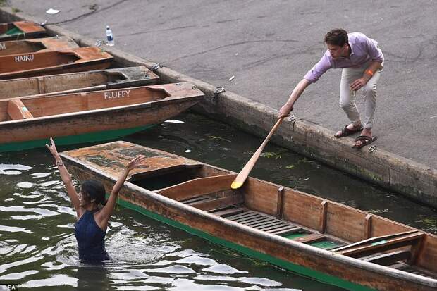 A passerby attempts to coax one female student back to shore after she jumped into the River Cam this morning