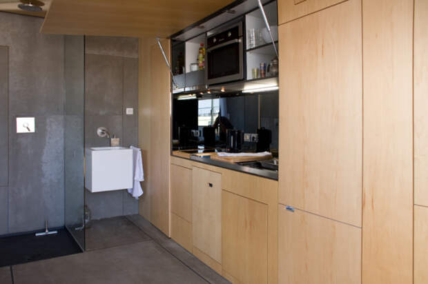 В левую часть стены встроена полноценная кухня и холодильник.