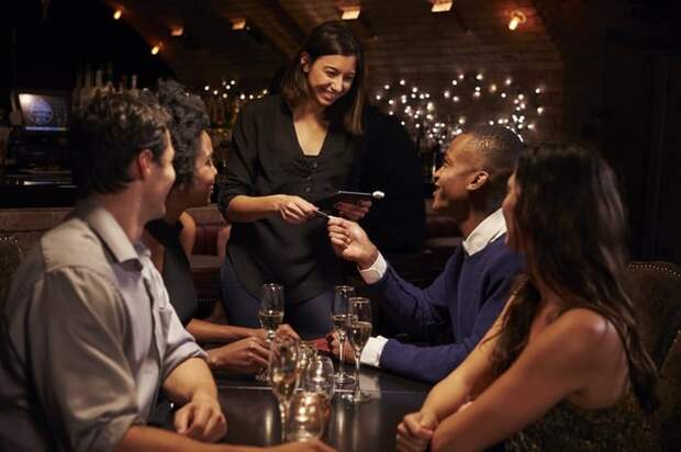 A table of four paying the bill with a credit card at a restaurant.