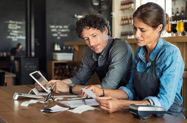 A couple sitting at a table and looking through paperwork together.
