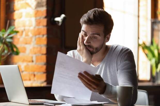 A man looking distressed while reading his credit card bill.
