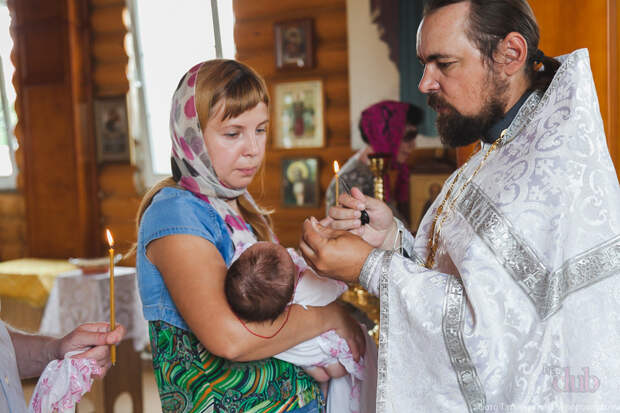 Женщина на крещении ребенка, батюшка читает над ней разрешительную молитву